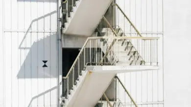 High stairway of contemporary stairway with metal railing of white wall of building in sunlight