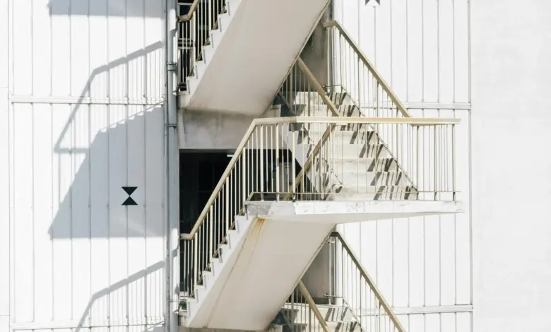 High stairway of contemporary stairway with metal railing of white wall of building in sunlight